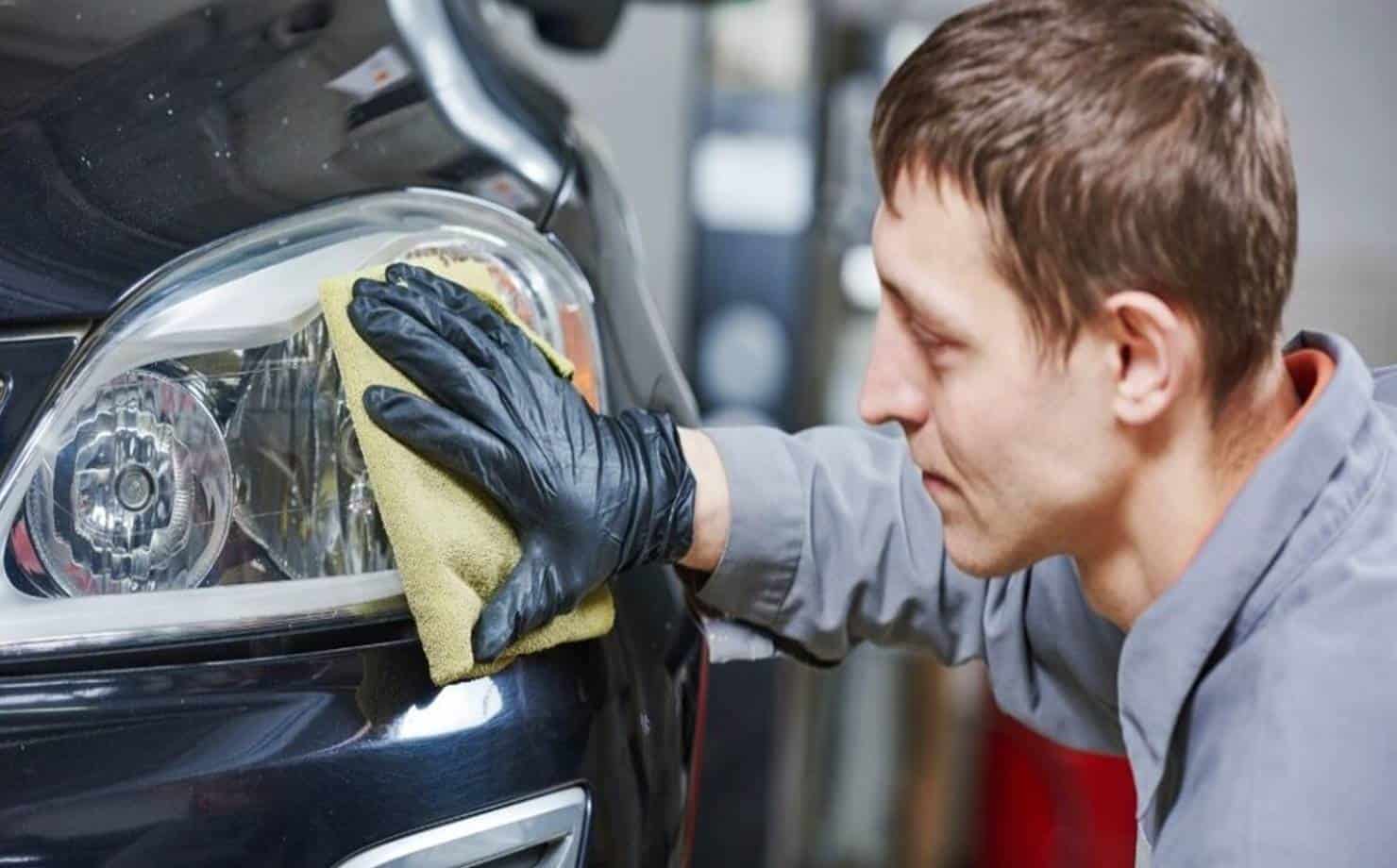 Homem limpando o farol do carro